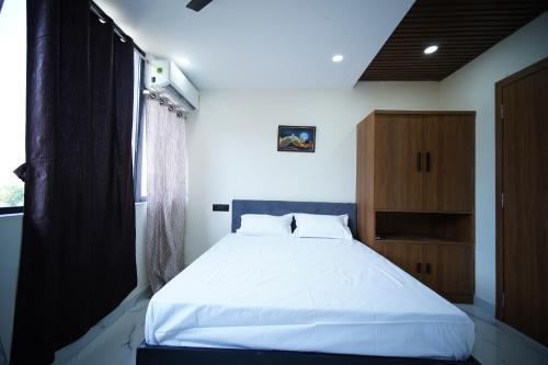 a bedroom with a white bed and a wooden cabinet at sinhgad hills in Kharakvasla
