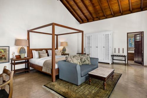 a bedroom with a canopy bed and a blue chair at The Postcard Galle in Galle