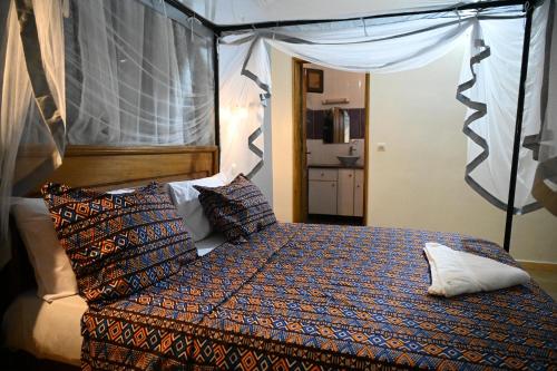 a bedroom with a bed with a canopy and pillows at la villa du parc in Niaga