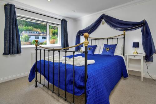 a bedroom with a bed with blue sheets and a window at Finest Retreats - Dyffryn in Betws-y-coed