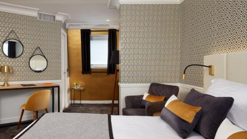 a bedroom with a bed and a desk and a chair at Hôtel le Royal Rive Gauche in Paris