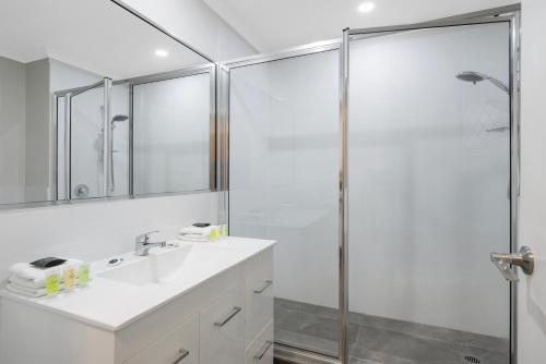 a white bathroom with a shower and a sink at Elizabethan Lodge in Melbourne