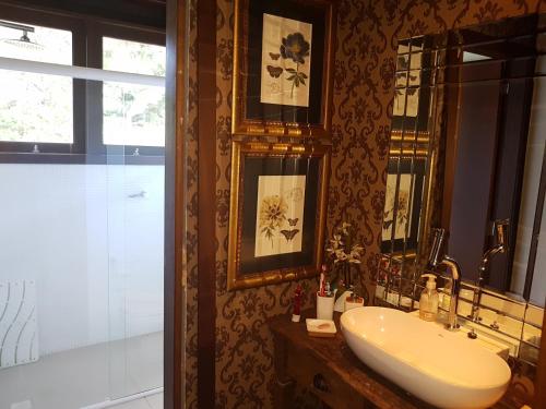 Un baño con lavabo, espejo y ducha. en Casa Luxo, en Balneário Camboriú