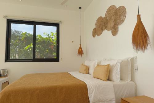 a bedroom with a bed with white sheets and a window at Trogon's Perch in San Isidro