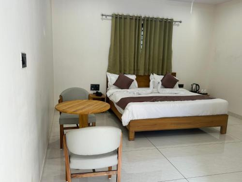 a bedroom with a bed and a table and a chair at Palm Glow Resort in Daisara