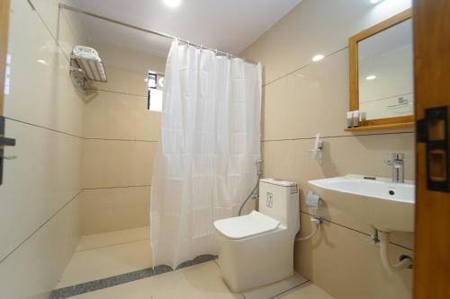 a bathroom with a toilet and a sink at Palm Glow Resort in Daisara