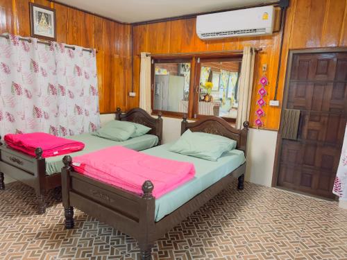 two beds with pink sheets in a room at โฮมสเตย์ริมน้ำน่าน บ้านอิ๊กขะหลิ๊ก in Nan