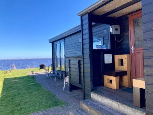 a wooden cabin with a view of the water at Waterfront holiday home Sonnenschein 4 persons with sauna in Anjum