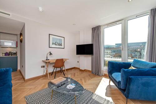 a living room with a blue couch and a table at Farringdon Serviced Apartments by LovelyStay in London