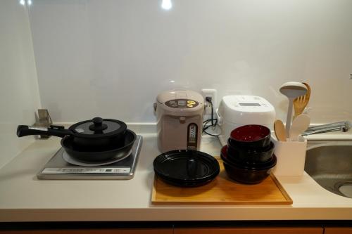a kitchen counter with a stove with pots and pans at Sumiyoshi Guesthouse 梦阁 粉浜の宿 in Osaka