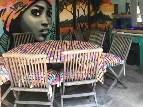 a table and chairs in front of a mural at Mantis and Moon Surf Paradise & Adventure Lodge in Hibberdene