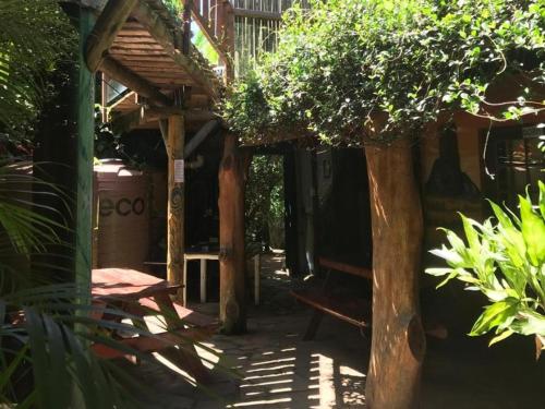 a patio with a table and a wooden structure at Mantis and Moon Surf Paradise & Adventure Lodge in Hibberdene