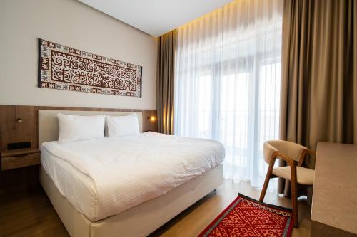 a bedroom with a bed and a desk and a window at Ustyurt boutique hotel in Aktau