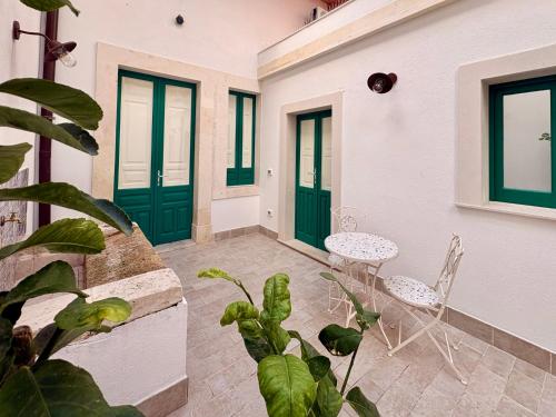 eine Terrasse mit grünen Türen und einem Tisch mit Stühlen in der Unterkunft Isula Antica in Floridia