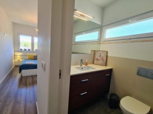 a bathroom with a sink and a toilet and a bed at Bright by the Beach - by CoH in Cruz Quebrada