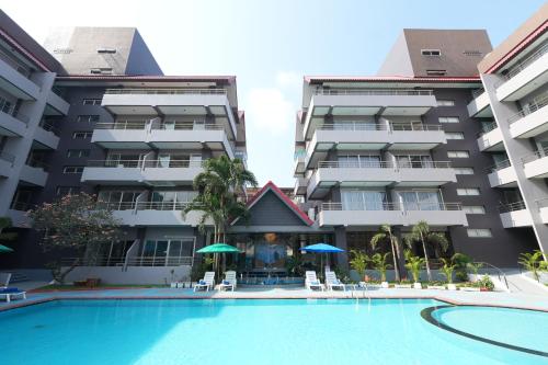a swimming pool in front of a building at The Holiday Resort Pattaya in Pattaya