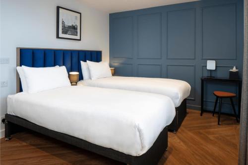 two beds in a hotel room with blue walls at Station Suites Aparthotel in Middlesbrough