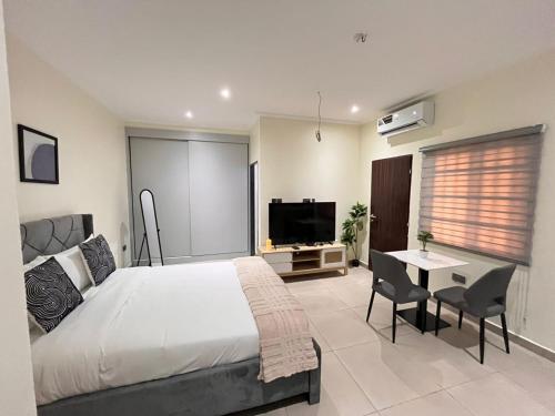 a bedroom with a bed and a table and a television at Veron, Dzorwulu in Accra
