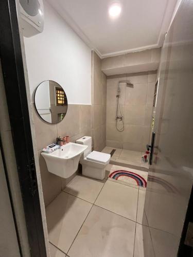 a bathroom with a sink and a toilet and a mirror at Veron, Dzorwulu in Accra