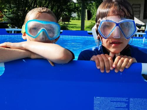 two children wearing goggles and swimming goggles in a swimming pool at Klarysewo bliżej Słońca in Mrągowo