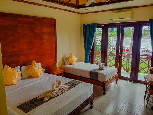 a bedroom with two beds and a balcony at Sengahloune Villa in Ban Khon
