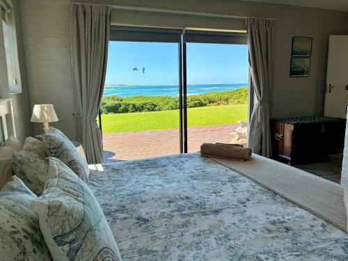 a bedroom with a large bed with a view of the ocean at Godolphin beach house in Cape St Francis