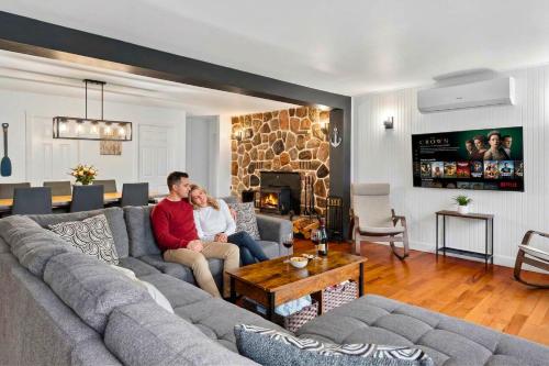 a man and woman sitting on a couch in a living room at Bécassines Private Spa & Pool table , Waterfront in Nominingue