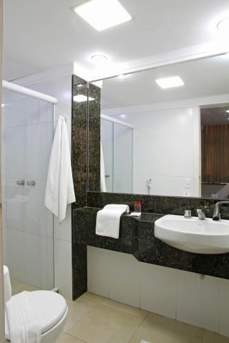 a bathroom with a sink and a toilet and a mirror at Malibu Palace Hotel in Cabo Frio