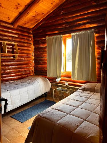 a bedroom with two beds in a log cabin at cabaña Quovadis in Trevelín