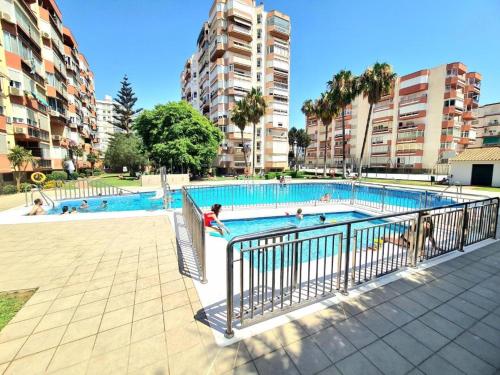 a swimming pool with people in it with buildings at EL ALTILLO- HOME RENt MALAGA in Torre del Mar