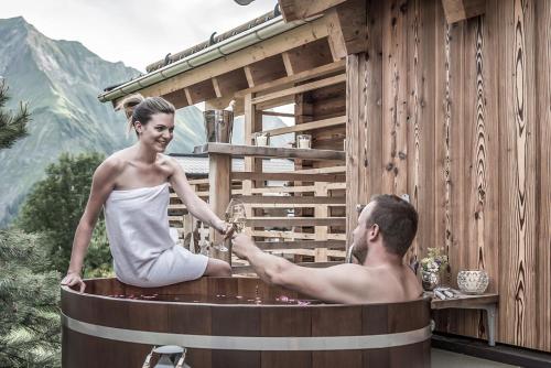 a woman sitting in a hot tub with a man at Aadla Walser-Chalets mit privater Sauna, Hotpot und Hotelservice in Schröcken