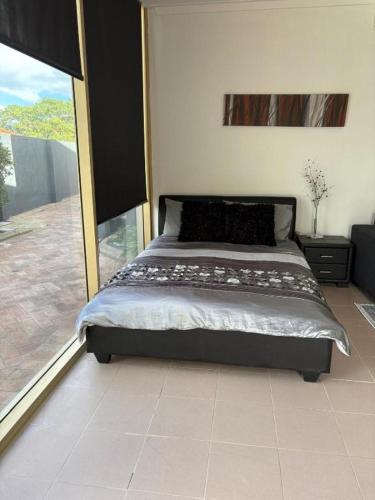 a bedroom with a bed and a large window at The Studio on Barberry with a Pool in Perth