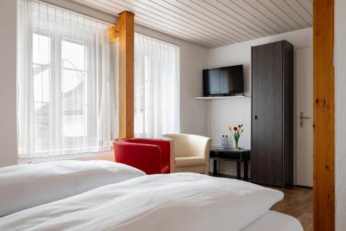 a bedroom with a bed and a chair and a television at Hotel Altstadt in Erlach
