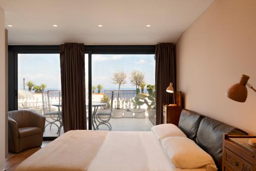 a bedroom with a bed and a couch and a balcony at Maison de Charme Taormina with private jacuzzi in Taormina