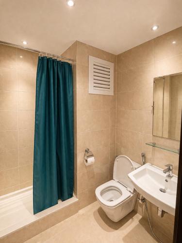a bathroom with a toilet and a green shower curtain at Appartement standing terrasse privative et piscine - Kariat Cabo in Cabo Negro
