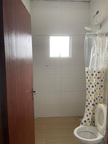 a bathroom with a toilet and a shower curtain at Ape Bianck's in Ilha Comprida