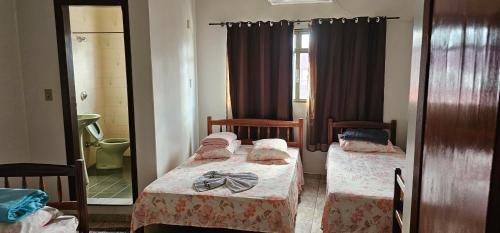 a bedroom with two beds and a mirror at Hotel Monarca Paracatu in Paracatu