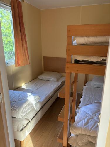two bunk beds in a room with a window at camping de la mottelette in Forest-Montiers