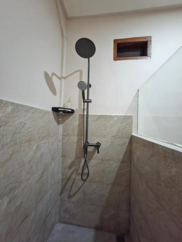 a shower with a shower head in a bathroom at Iza home stay in Senaru