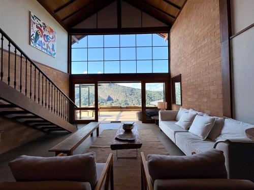 a living room with a couch and a large window at Casa 02 Monte Boa Vista - Casa de 4 Suítes com Vista Deslumbrante in Teresópolis