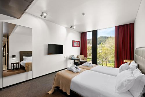 a hotel room with two beds and a large window at Axis Viana Business & SPA Hotel in Viana do Castelo