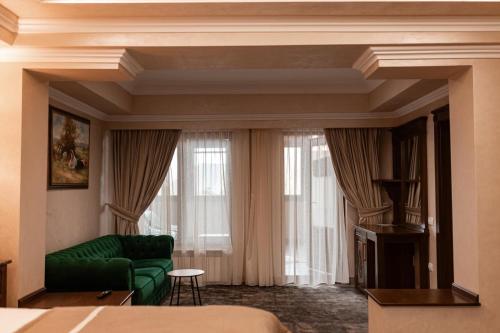 a living room with a green couch and windows at Pensiunea Eden in Târgu Neamț