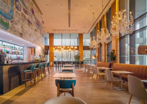 a restaurant with tables and chairs and chandeliers at Hilton London Heathrow Airport Terminal 5 in Hillingdon