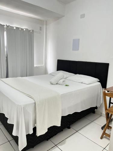 a bedroom with a bed with a white blanket on it at its hotel in Itapetinga