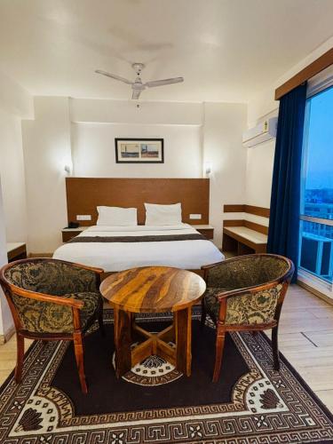 a bedroom with a bed and a table and chairs at Golden Pent House in Lucknow