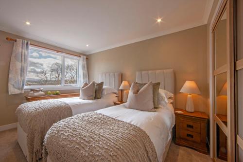 two beds in a room with two lamps and a window at Cuilreigh, North Connel in Oban