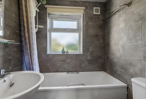 a bathroom with a tub and a sink and a window at Landscove Chalet 19 in Brixham