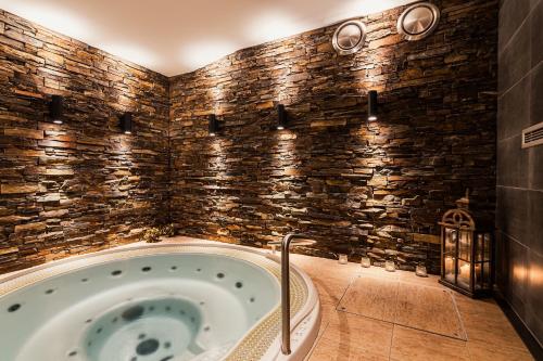 a bath tub in a room with a stone wall at Hotel Toč in Lipova Lazne