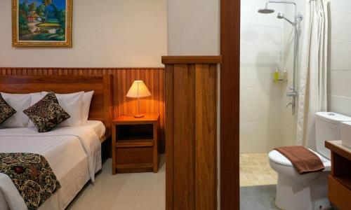 a bedroom with a bed and a bathroom with a shower at Cening Ayu Sanur in Sanur