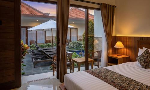 a bedroom with a bed and a balcony with a patio at Cening Ayu Sanur in Sanur
